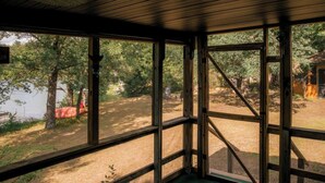 Una cabaña con ventanas amplias, techo de madera y vista a un lago y árboles.