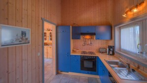Una cocina compacta con armarios azules, estufa y lavamanos.
