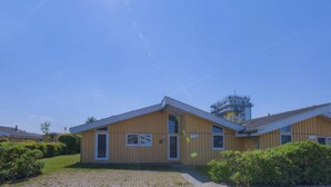 A building with a sloped roof, a paved driveway, and a clear sky. - Skandinavisches Ferienhaus in Rechlin (Rechlin)
