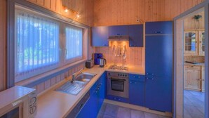 Une cuisine de taille réduite avec des murs en bois, un évier, une cuisinière et des placards bleus.