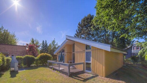 Une maison en bois d’un seul étage, dotée d’un porche couvert et d’une petite terrasse.