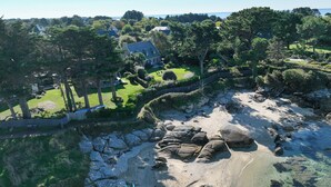 A coastal property with a sandy beach, a landscaped garden, and a view of the sea.
