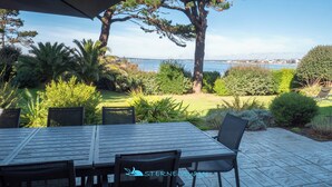 An outdoor patio with a table and chairs, overlooking a body of water and a distant shoreline.