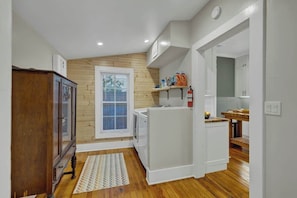 A compact kitchen with wooden flooring, a built-in stove, and a window with blinds.