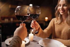 Two people toasting with wine glasses at a table with candles.