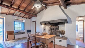 A rustic kitchen with a wooden table, chairs, and a fireplace.