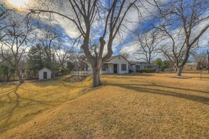 A residential area with a house, a small shed, and a tree in the foreground. - Leicht Haus Hot-Tub & FirePit 5 blks to Main St! (Fredericksburg)