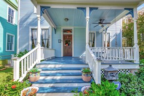 A porch with a white railing, a wooden door, and a blue ceiling. - 1900 Storm-Survivor Home • Huge Yard + Porches • 3-Min Drive to Beach (Galveston)