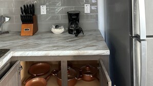A kitchen with wooden cabinets, a marble countertop, a coffee maker, and copper pots. - 516 - House in West Yellowstone (West Yellowstone)