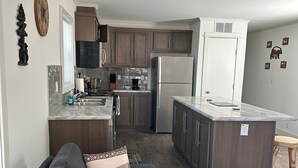 A modern kitchen with dark wooden cabinets, a stainless steel refrigerator, and a marble countertop. - 516 - House in West Yellowstone (West Yellowstone)