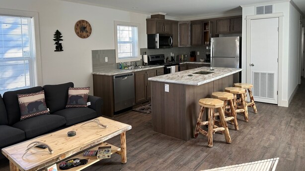 A modern kitchen with a central island, wooden stools, and a black sofa with patterned cushions. - 516 - House in West Yellowstone (West Yellowstone)