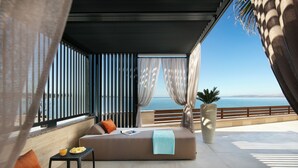 A modern outdoor seating area with a sofa, cushions, a small table with a bowl of fruit, and a potted plant. - Infinity Blue and Golden Sky (Vir)