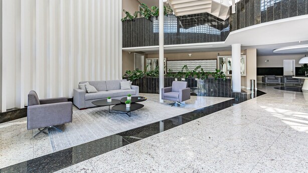A spacious lobby with a grey sofa, armchairs, and a coffee table. There are plants and a staircase connecting the floors. - Gastronomy | Gym | Pool #ITA10 (Florianópolis)