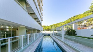 A modern building with a long, narrow pool in the center, surrounded by glass railings and a white exterior. - Gastronomy | Gym | Pool #ITA10 (Florianópolis)