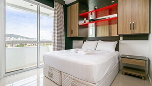 A modern bedroom with a large bed, a sliding glass door to a balcony, and built-in wooden cabinets with red shelves. - Gastronomy | Gym | Pool #ITA10 (Florianópolis)