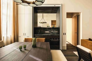 A modern dining area with a wooden table, two green glassware, and a bench. - Mondovi Luxury Suites (Paris)