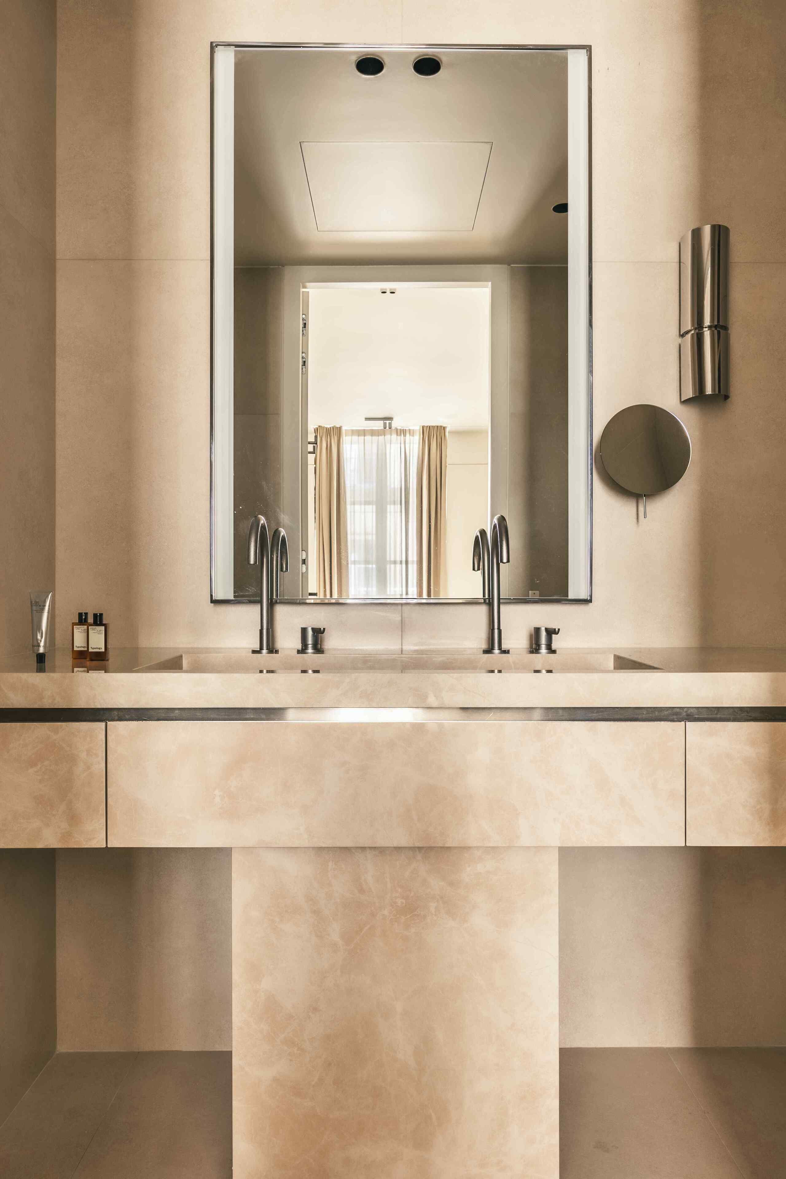 A modern bathroom with a large mirror, two sinks, and a toilet.