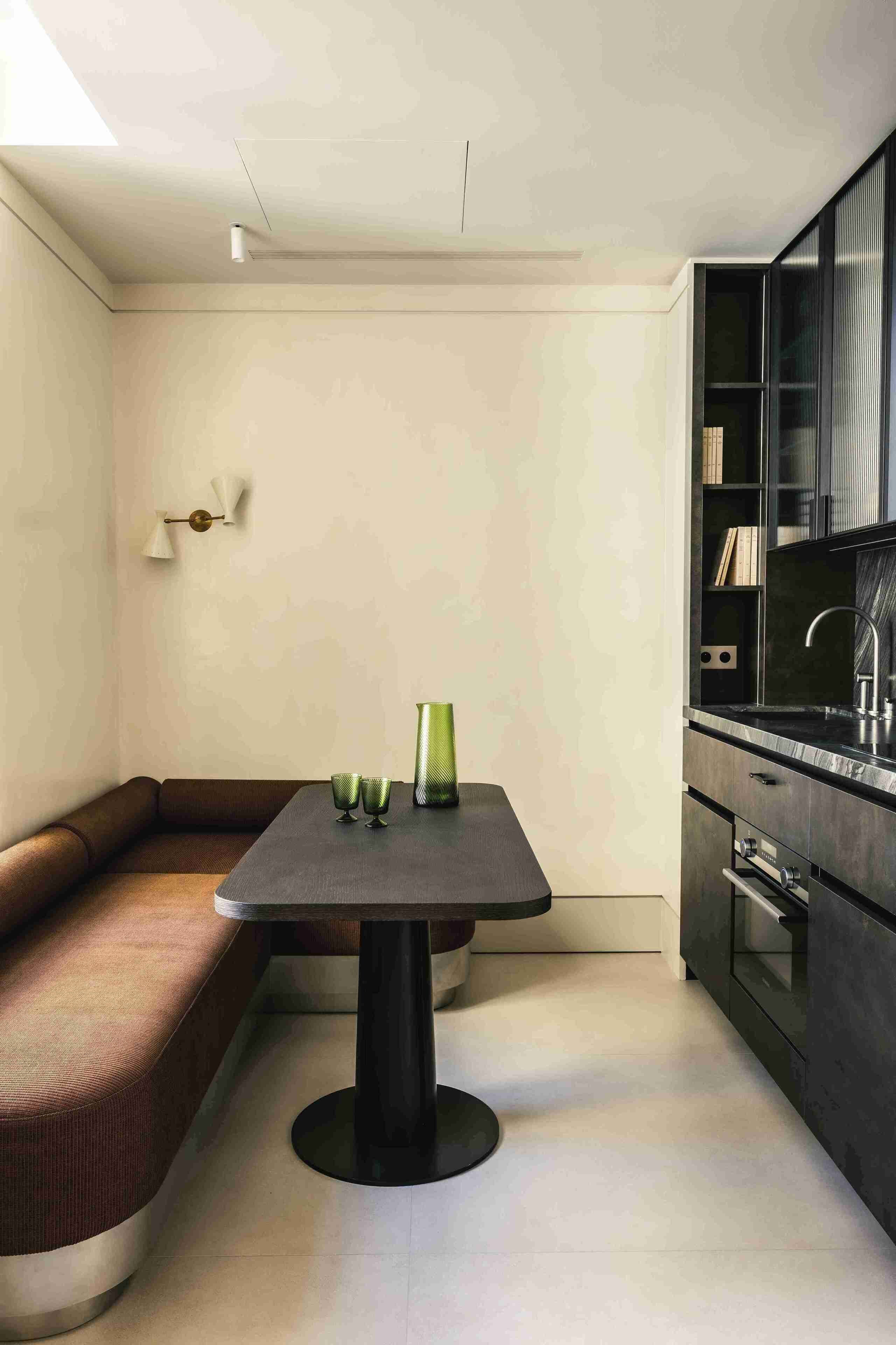 A modern kitchen with a dark countertop, a built-in oven, and a black cabinet with shelves.