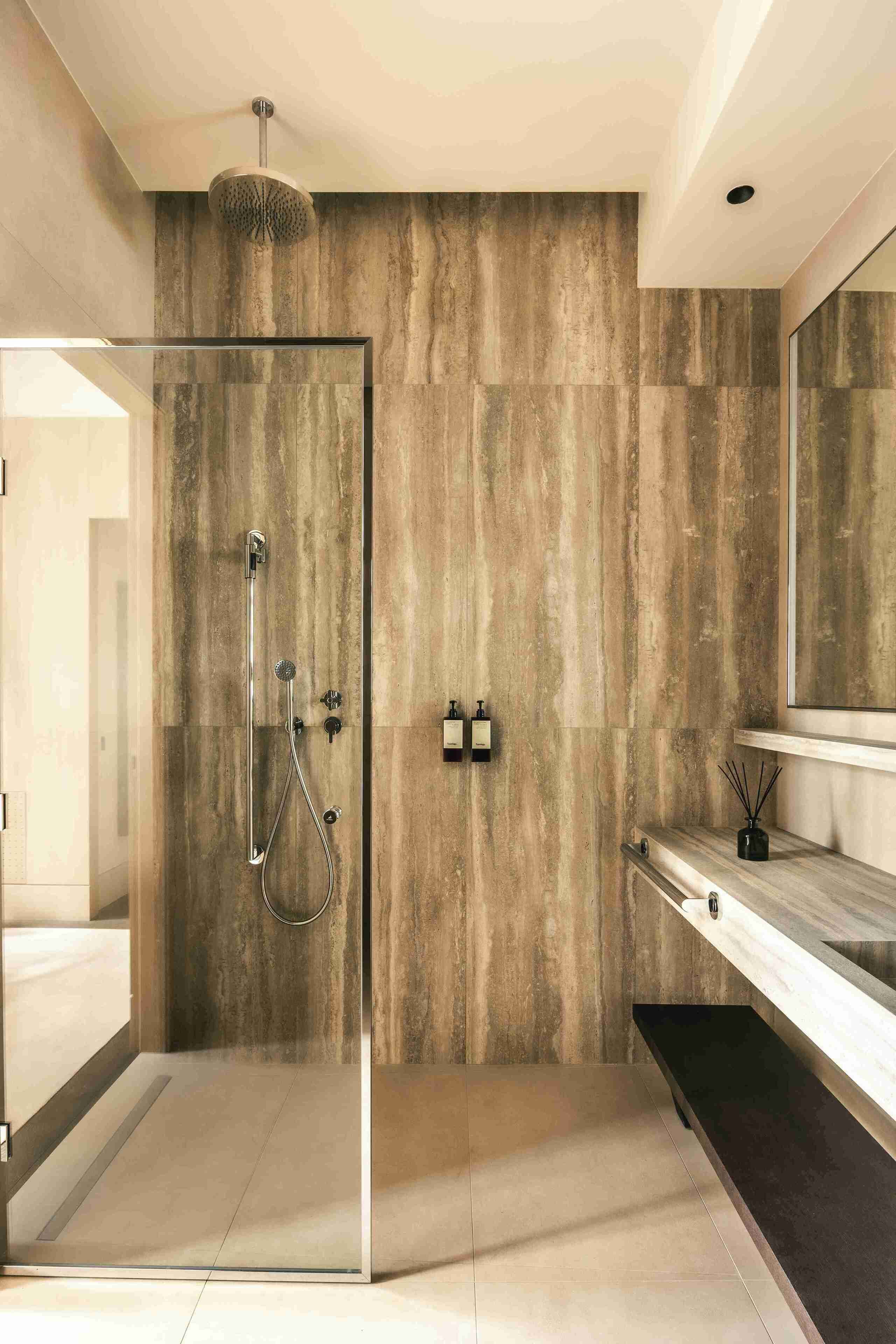 A modern bathroom with a glass-enclosed shower, a wooden wall, a large mirror, and a minimalist vanity.