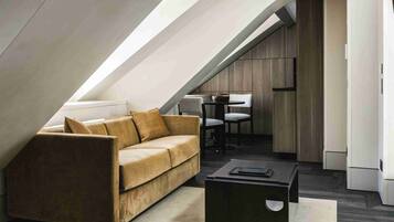 A modern loft apartment with a sloped ceiling, a sofa, a dining table, and a coffee table.