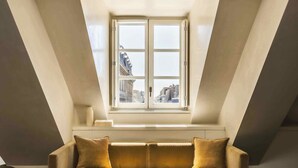A cozy loft bedroom with a large window, a sofa, and a coffee table. - Mondovi Luxury Suites (Paris)