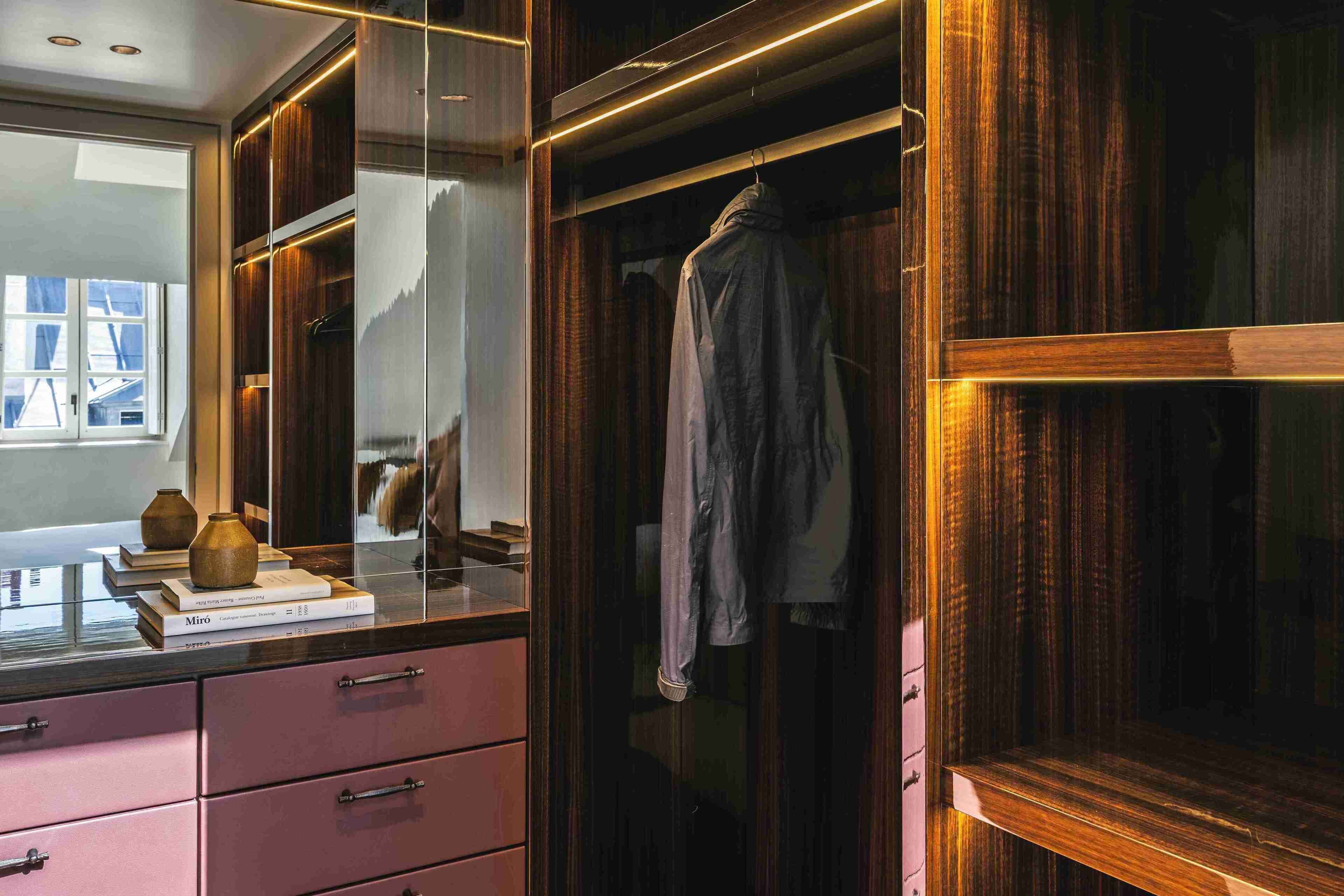 A modern closet with wooden doors, a mirror, and a hanging garment.