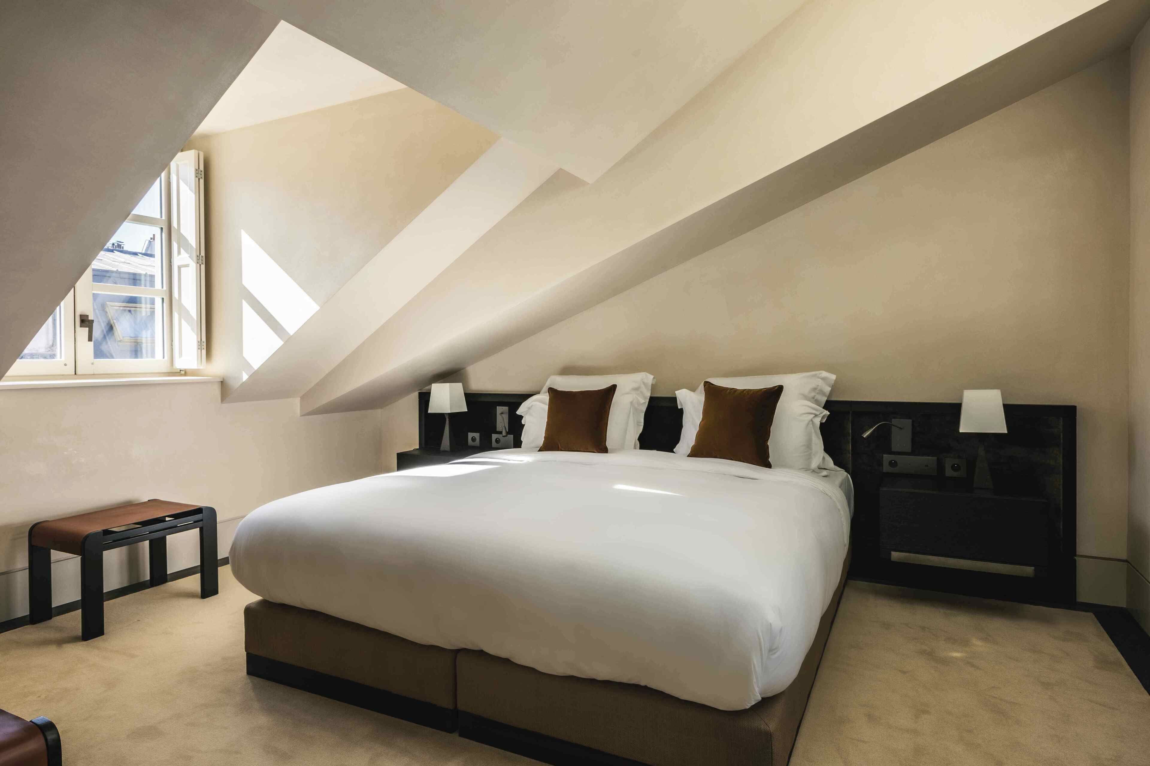 A bedroom with a large bed, a bench, and a nightstand.