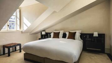 A bedroom with a large bed, a bench, and a nightstand.