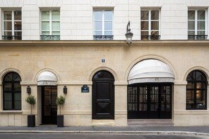 A building with a row of arched windows, a black door, and a sign indicating the address. - Mondovi Luxury Suites (Paris)