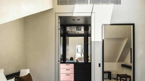 A modern hotel room with a large bed, a desk, and a walk-in closet. - Mondovi Luxury Suites (Paris)