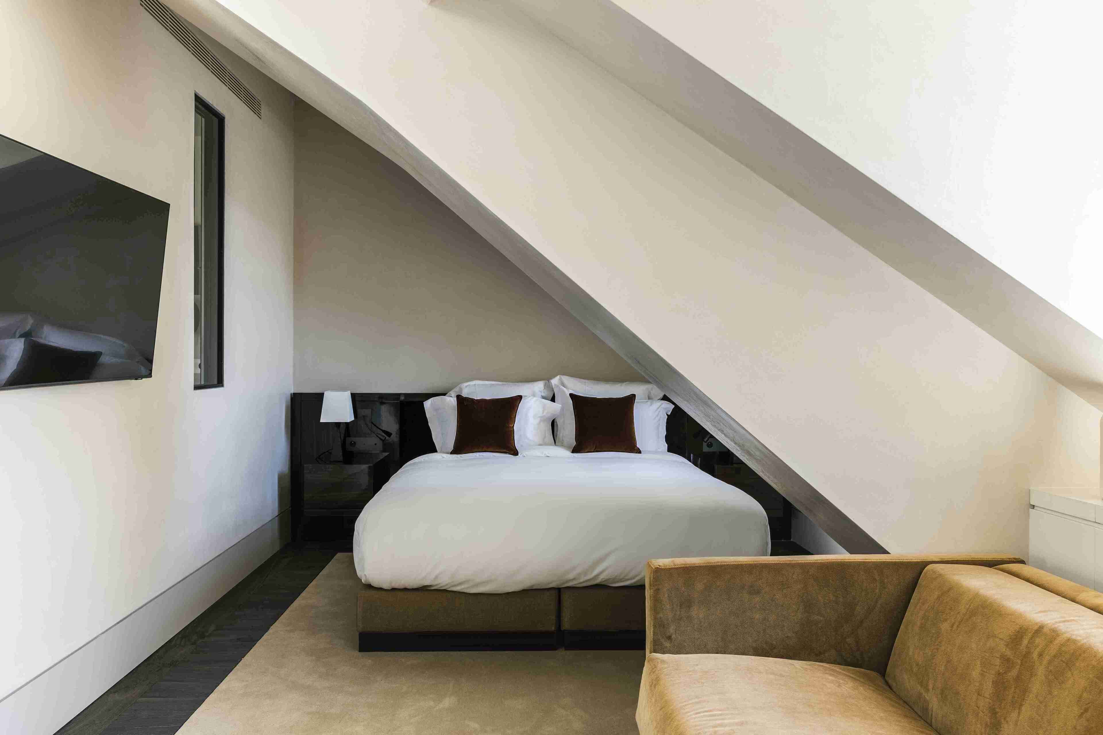 Une chambre à coucher avec un lit, une chaise et un plafond en pente.