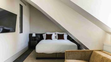 A bedroom with a bed, a chair, and a sloped ceiling.