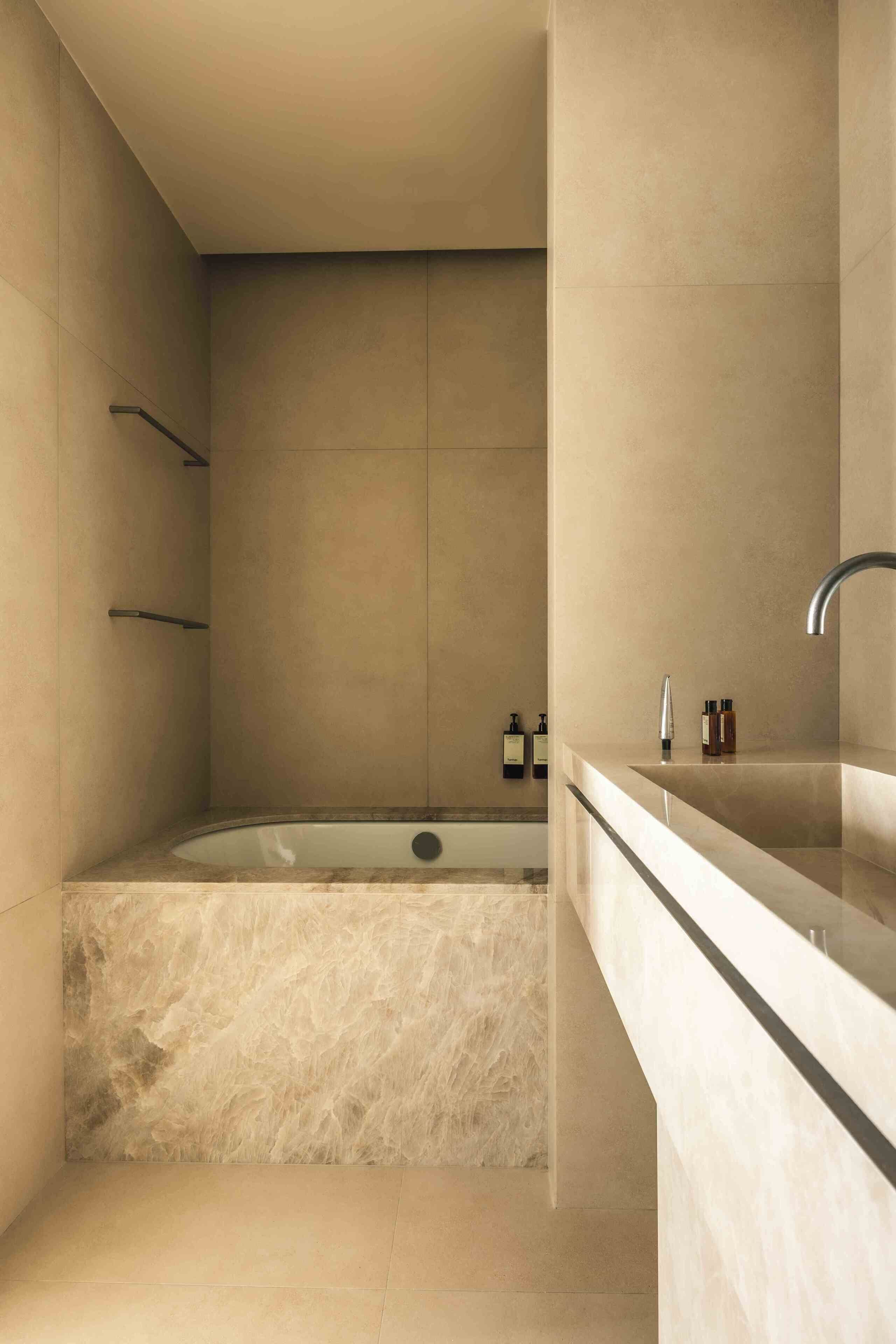 A modern bathroom with a freestanding bathtub, a glass-enclosed shower, and a marble countertop with a sink and faucet.