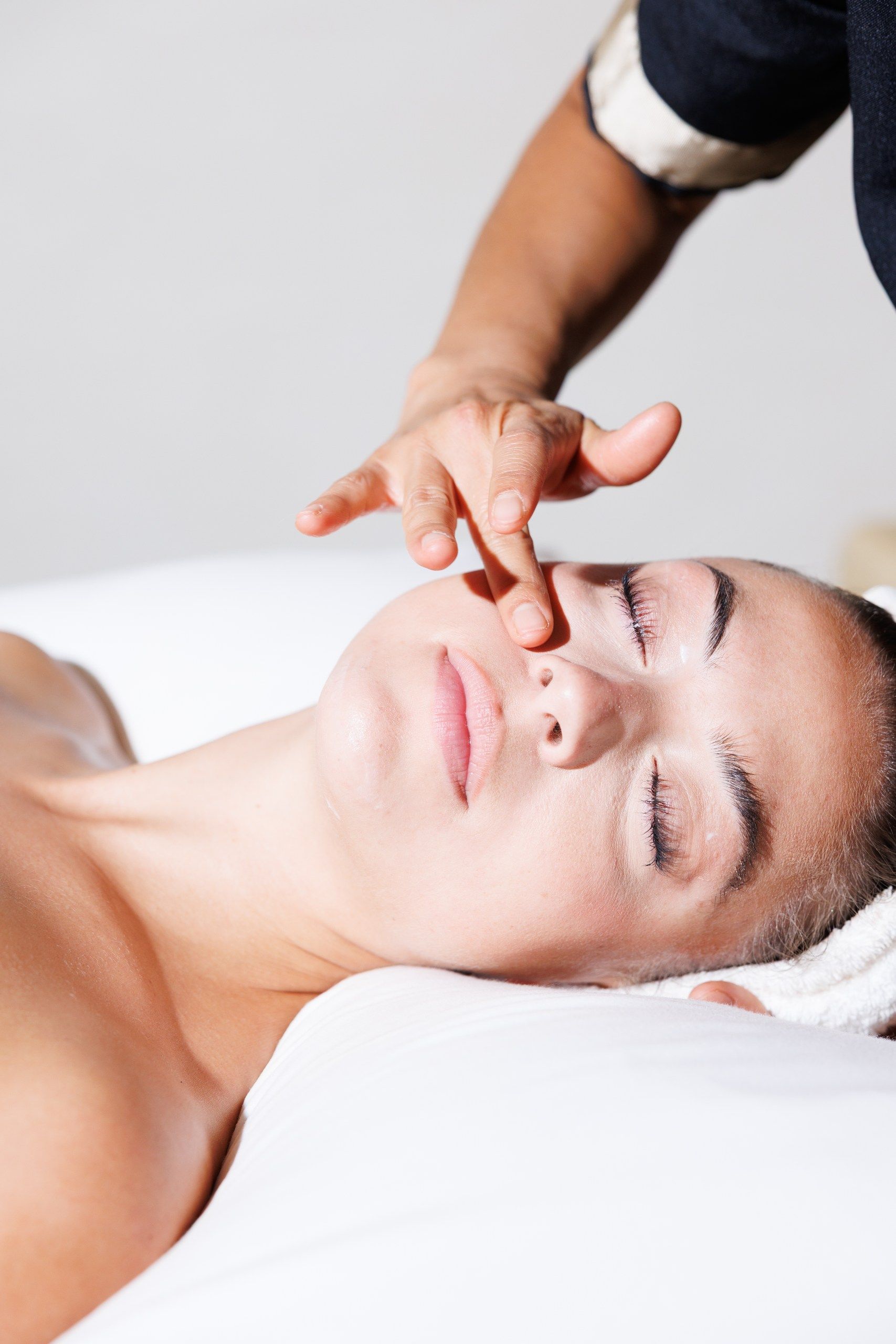 A person lying down with a hand on their face, possibly receiving a facial treatment.