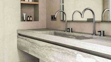 A modern bathroom with a marble sink, built-in shelves, and a large mirror.