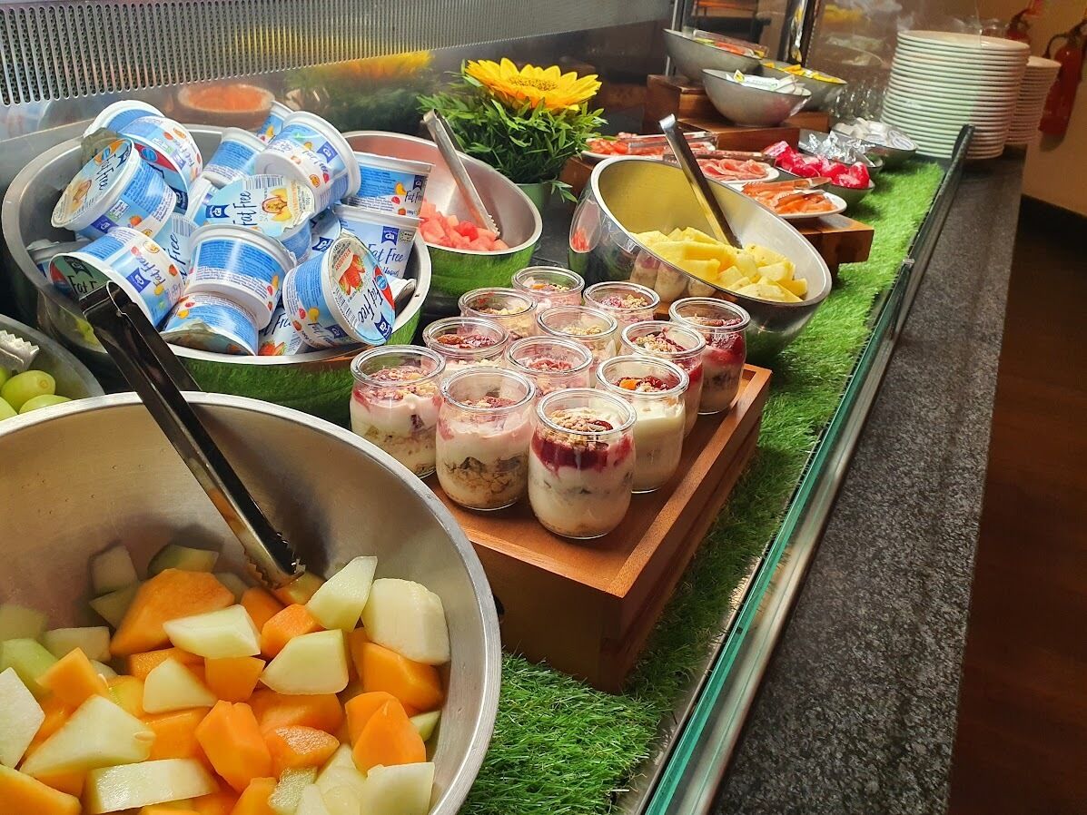 Un bufé con diversos alimentos, incluyendo yogur, frutas y postres.