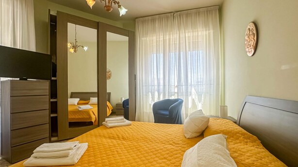 Ett hotellrum med en stor säng, en garderob, ett skrivbord och en stol.