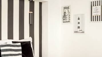 A modern bedroom with a large bed, black and white striped headboard, and a pendant light.