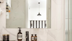 Une salle de bain moderne avec un meuble-lavabo blanc, un grand miroir et un porte-serviettes suspendu.