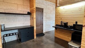 A modern kitchen with wooden walls, a concrete floor, and a black countertop. - CHRISTOVAL CASITAS #5 KING ROOM (Christoval)