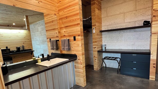 A modern kitchen with wooden paneling, a built-in island, and a stone backsplash. - CHRISTOVAL CASITAS #5 KING ROOM (Christoval)
