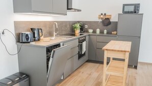 A compact kitchen with grey cabinets, a wooden table, a microwave, and a coffee maker.