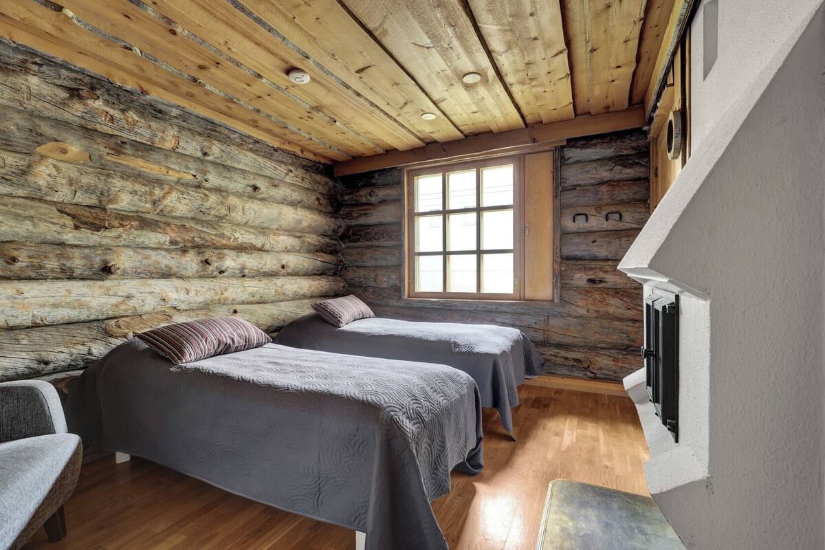 Una habitación de cabaña de madera con dos camas, una ventana y techo de madera.