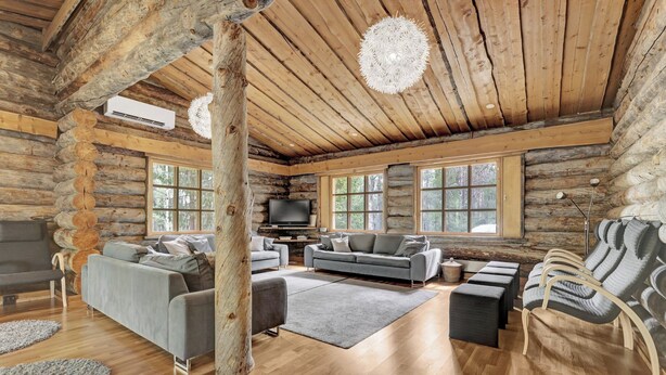 A log cabin interior with a fireplace, sofas, and a television. - Bliss Adventure Lodge (Pelkosenniemi)