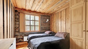 A cabin-style room with two beds, a wooden ceiling, a large window, and a wardrobe. - Bliss Adventure Lodge (Pelkosenniemi)