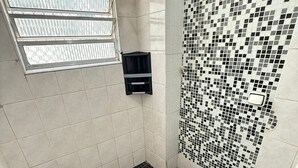A bathroom with a black and white checkered floor, a white toilet, and a shower area with a tiled wall. - Feet in the Sand Tupi Beach (Praia Grande)