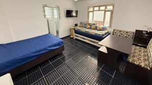 A room with a bed, a desk, a chair, a television, and a window. - Feet in the Sand Tupi Beach (Praia Grande)