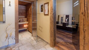 A wooden interior with a glass door leading to a sauna area, a wooden bench, and a small table with a lamp. - The Rotspitz / Achensee (Tirol)