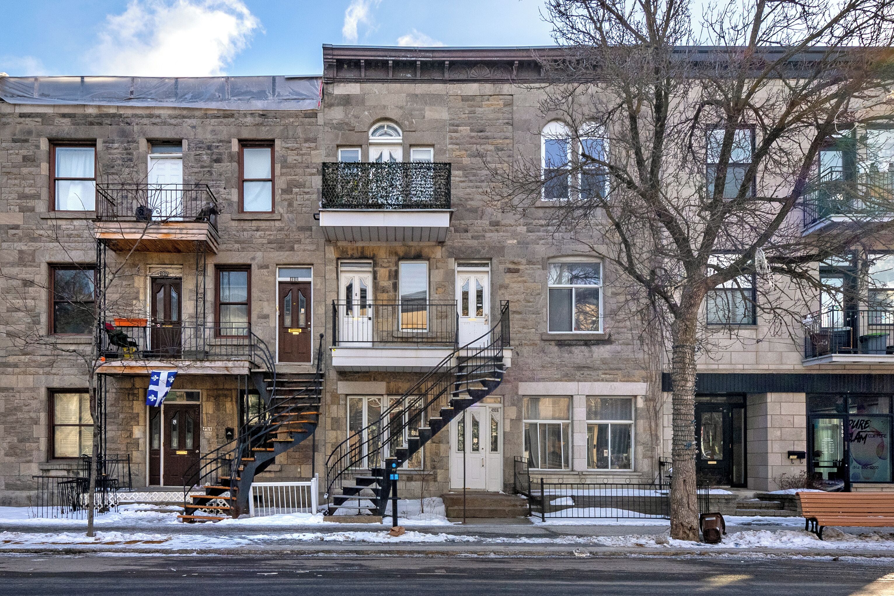 A multi-story building with a stone facade, multiple windows, and a fire escape.