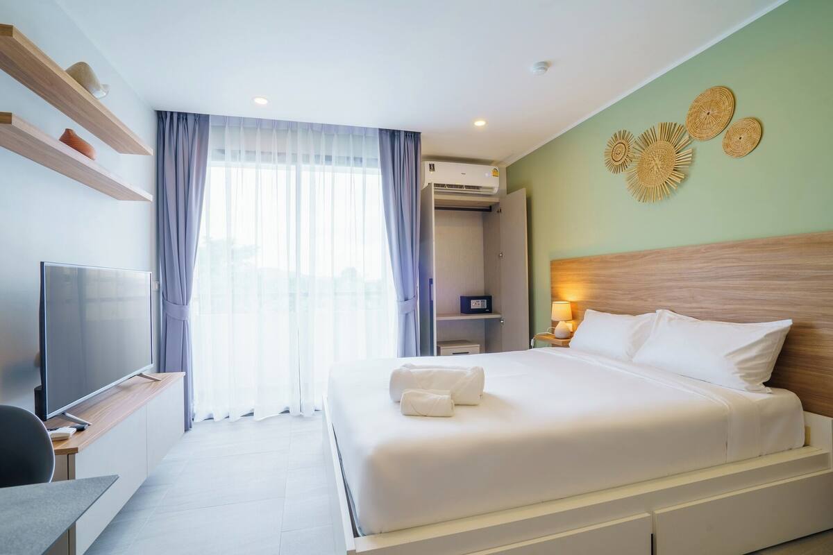 A hotel room with a bed, a TV, a desk, and a wardrobe.